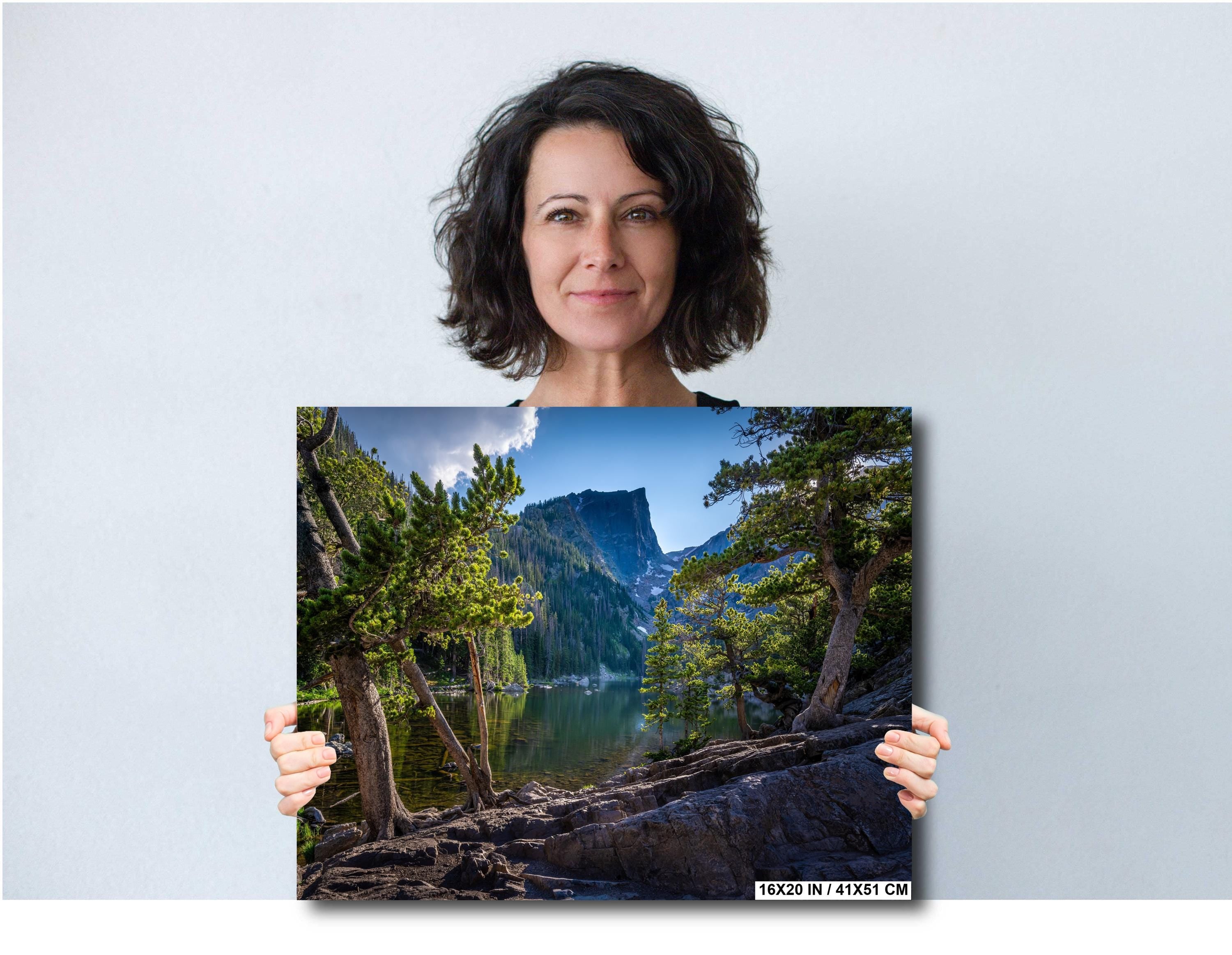 Woman holding a print of a scenic landscape of Bear Lake in Rocky Mountain National Park.