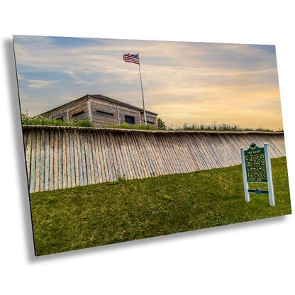 A historical marker sign featuring the Fort Holmes sign with a background of a wooden fence and a flag, capturing a moment of history on Mackinac Island.